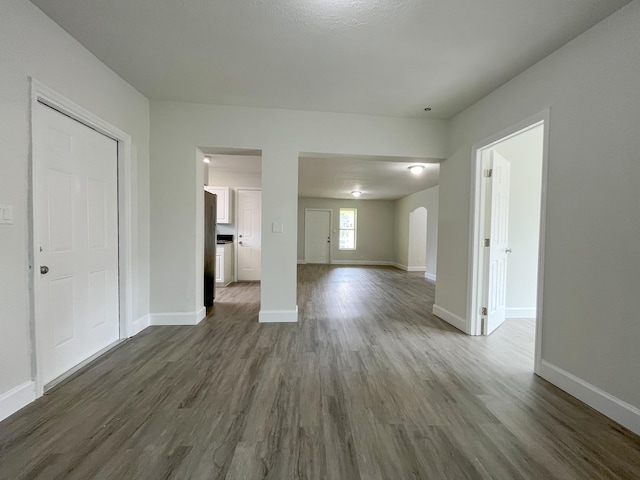 unfurnished living room with dark wood finished floors and baseboards