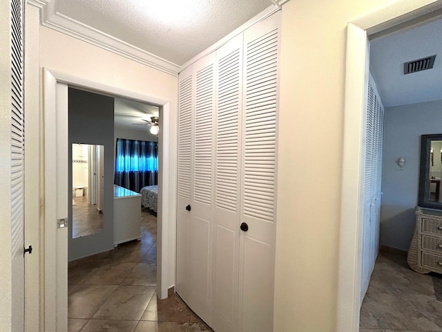 hallway with visible vents, crown molding, and a textured ceiling