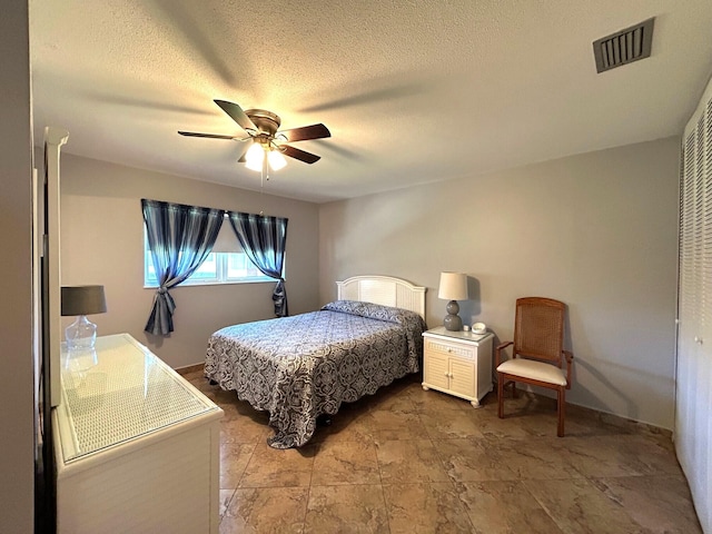 bedroom with a textured ceiling, visible vents, and a ceiling fan