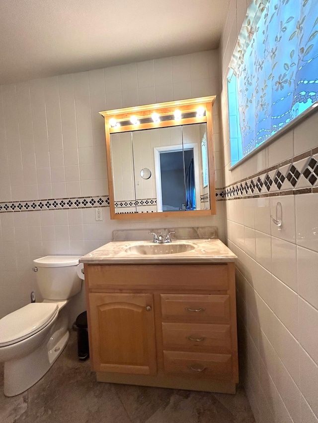 bathroom with tile walls, vanity, and toilet