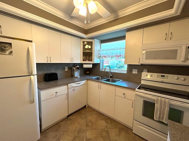 kitchen featuring white appliances, white cabinets, dark countertops, crown molding, and a sink