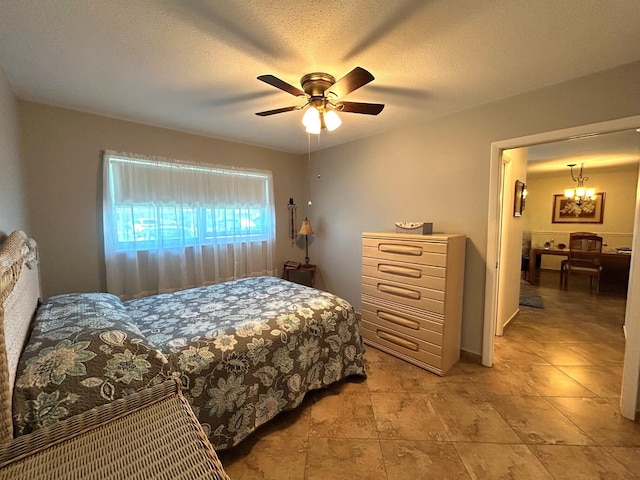 bedroom featuring a textured ceiling and ceiling fan with notable chandelier