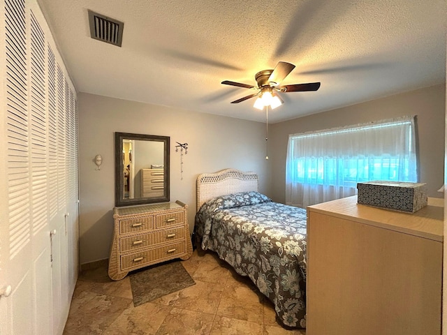 bedroom featuring a textured ceiling, a closet, visible vents, and a ceiling fan