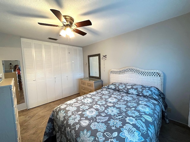 bedroom featuring a ceiling fan, a textured ceiling, visible vents, and a closet