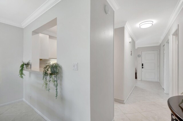 corridor featuring light tile patterned floors, baseboards, and ornamental molding