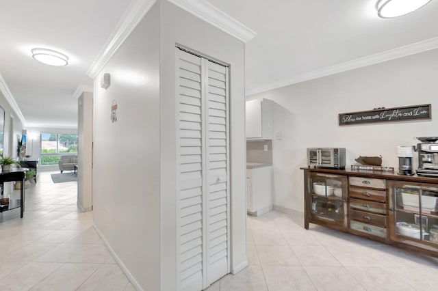 hallway with light tile patterned floors, crown molding, and baseboards