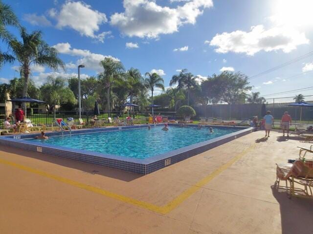 community pool with a patio and fence