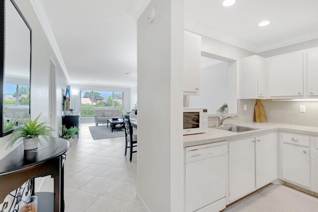 kitchen featuring a sink, white appliances, crown molding, and light countertops