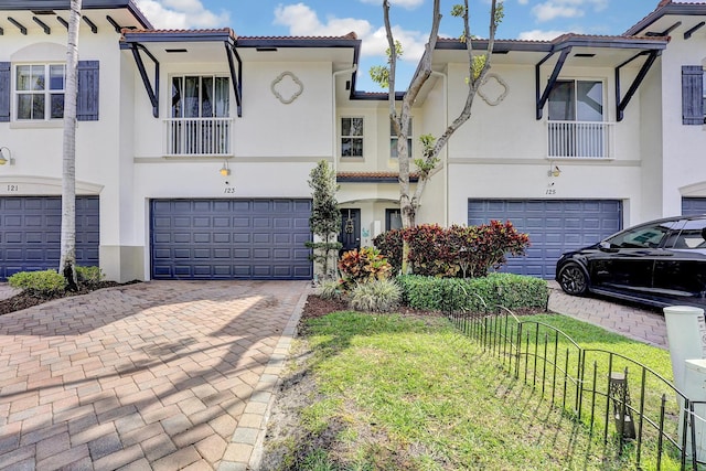 view of front of property with a tiled roof, decorative driveway, an attached garage, and stucco siding