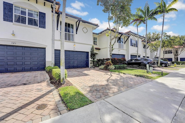 view of property featuring decorative driveway, an attached garage, a residential view, and stucco siding