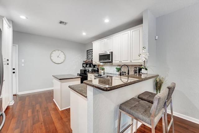 123 E Prive Cir, Delray Beach, FL 33445 - kitchen with stainless steel appliances, a center island, backsplash, baseboards, and dark wood-style flooring