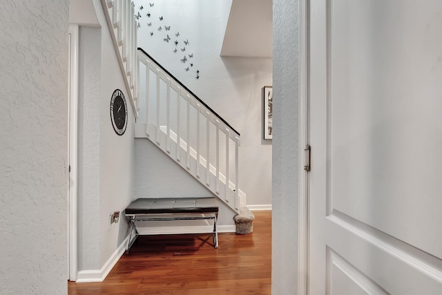 stairway with a textured wall, baseboards, and wood finished floors