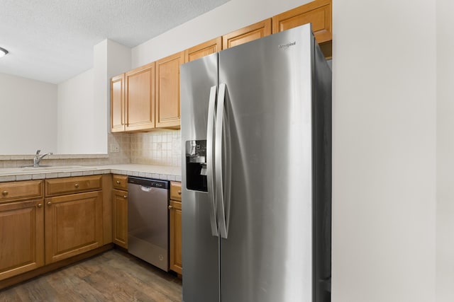 kitchen with decorative backsplash, dark wood-style floors, appliances with stainless steel finishes, a textured ceiling, and a sink