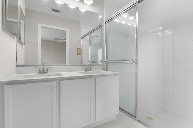 bathroom with double vanity, a ceiling fan, a sink, and tiled shower