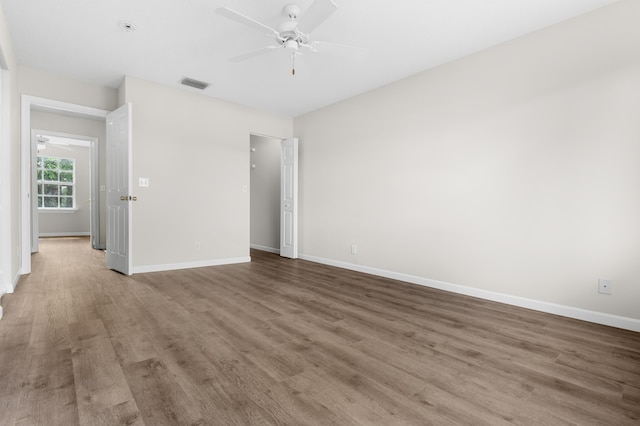 unfurnished bedroom with a ceiling fan, wood finished floors, visible vents, and baseboards