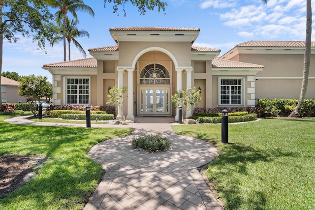 property entrance with a yard, french doors, a tile roof, and stucco siding