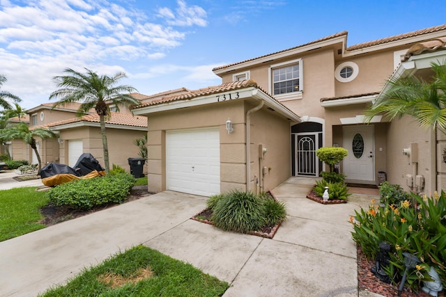 mediterranean / spanish-style home with driveway, a tiled roof, an attached garage, and stucco siding