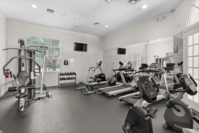 exercise room featuring baseboards, visible vents, and a textured ceiling