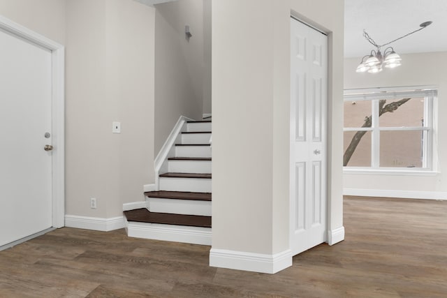 stairs with baseboards, a chandelier, and wood finished floors