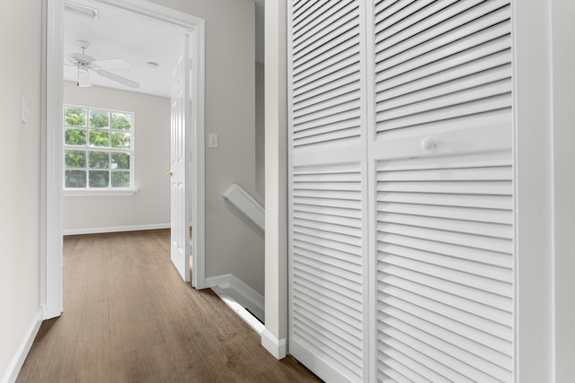 corridor with baseboards and wood finished floors