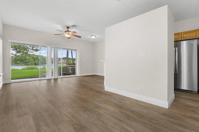 unfurnished living room with baseboards, visible vents, ceiling fan, and wood finished floors