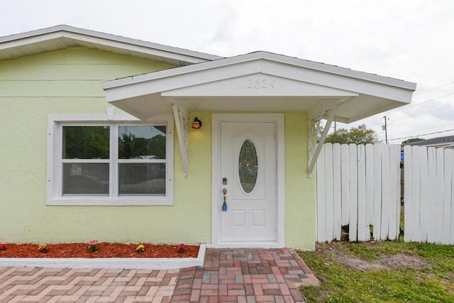 property entrance with fence and stucco siding