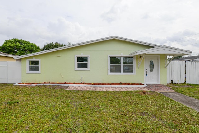 single story home with stucco siding, fence, and a front yard