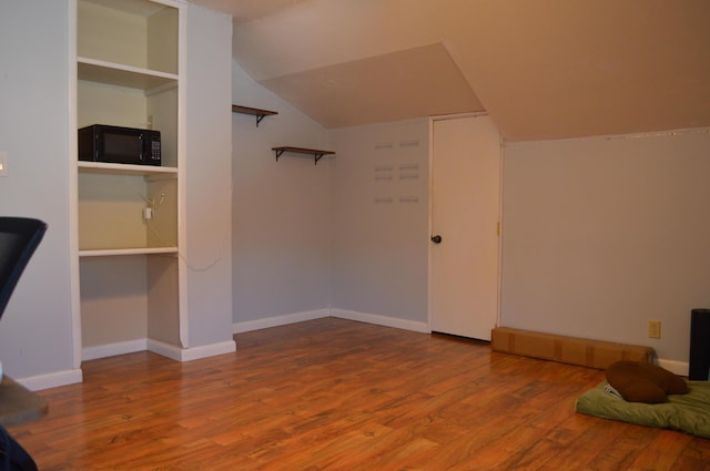 bonus room with baseboards, lofted ceiling, and wood finished floors