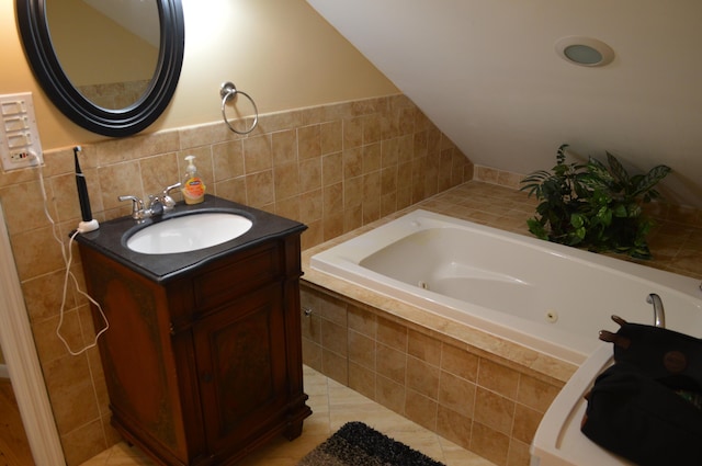 full bathroom with tile walls, a tub with jets, vanity, and tile patterned flooring