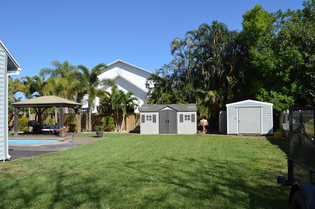 view of yard with a storage unit, a fenced backyard, a gazebo, an outdoor structure, and a fenced in pool