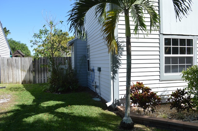 view of side of home with a yard and fence