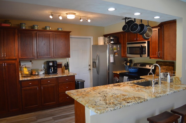 kitchen with appliances with stainless steel finishes, a breakfast bar area, a peninsula, and light stone countertops