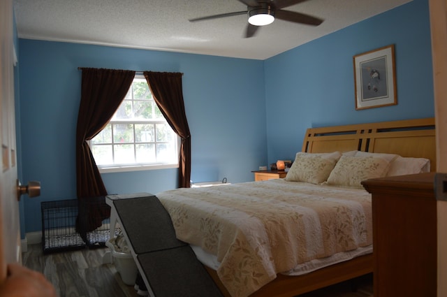 bedroom with a textured ceiling, a ceiling fan, and wood finished floors