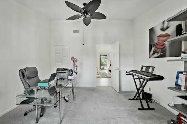 carpeted office with visible vents, ceiling fan, a towering ceiling, and baseboards