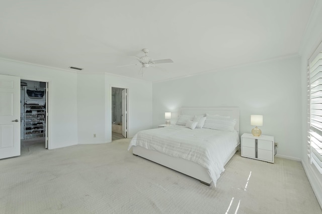 bedroom with carpet, visible vents, a spacious closet, ornamental molding, and a ceiling fan