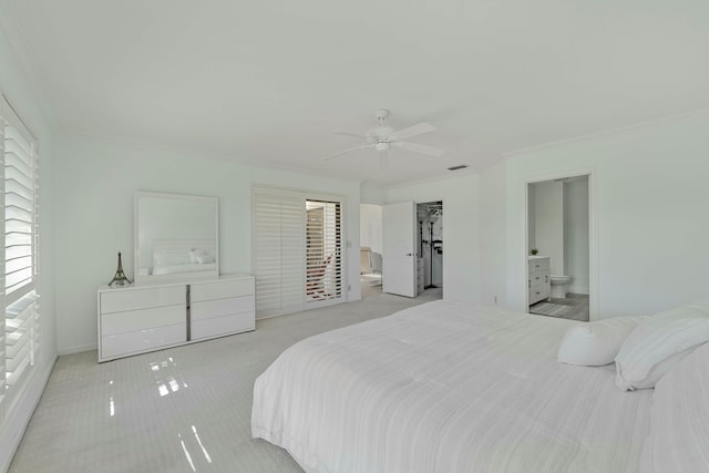 bedroom with carpet floors, a ceiling fan, visible vents, ensuite bath, and crown molding