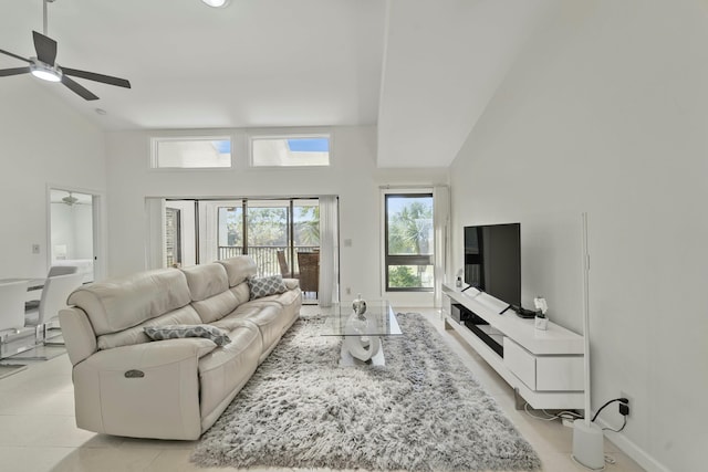 living room with a high ceiling, ceiling fan, baseboards, and light tile patterned floors