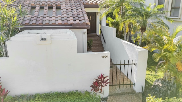 view of property exterior featuring a tiled roof, a fenced front yard, a gate, and stucco siding