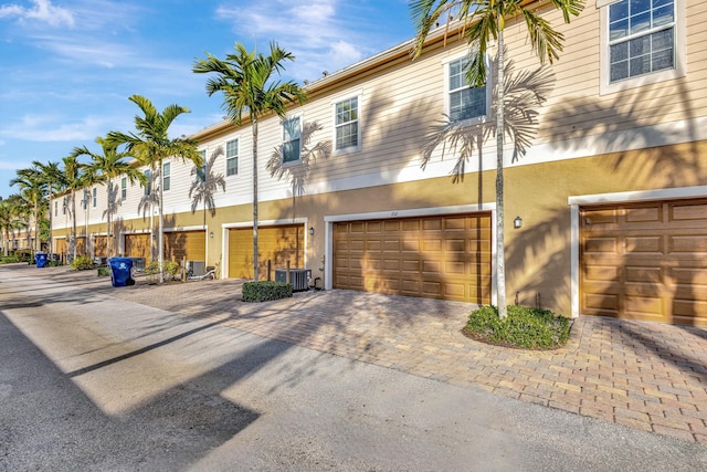 view of front of home with stucco siding, a garage, cooling unit, and driveway