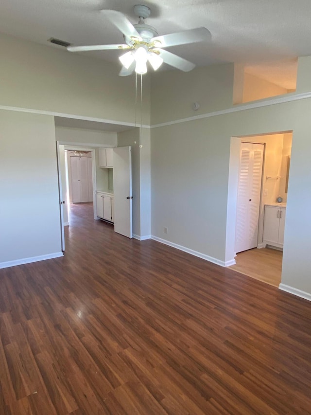 unfurnished room with visible vents, baseboards, dark wood finished floors, ceiling fan, and vaulted ceiling