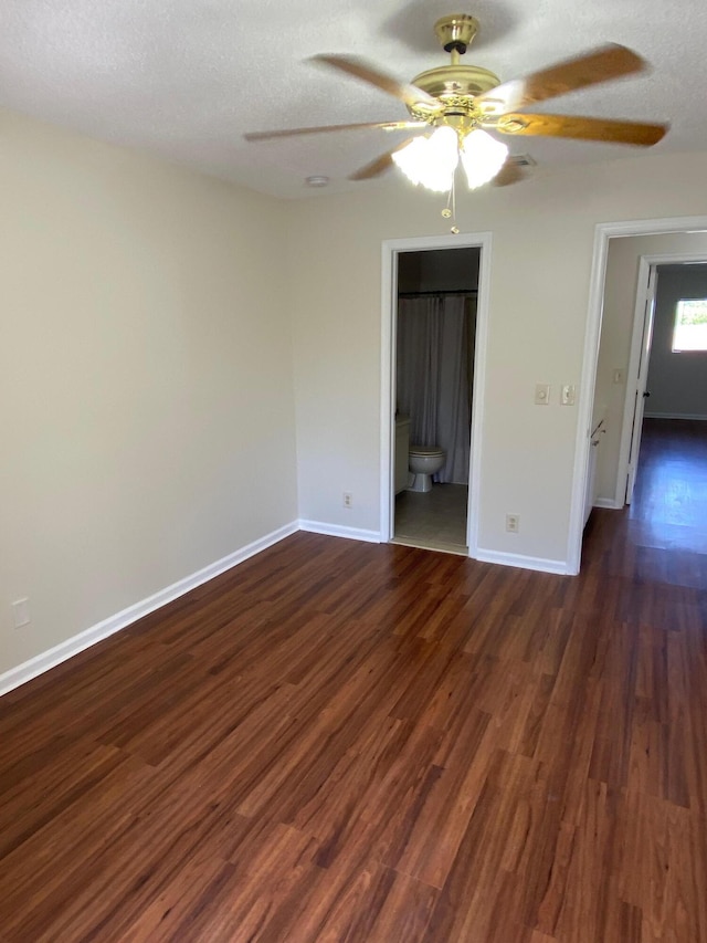 unfurnished room featuring dark wood-type flooring, a textured ceiling, and baseboards