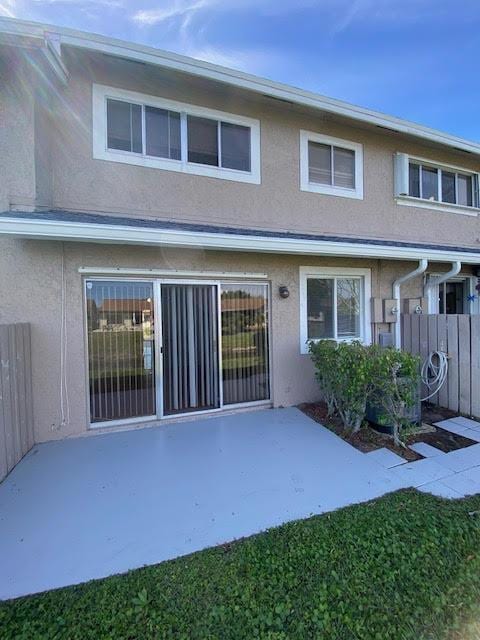 rear view of property featuring a patio area, fence, and stucco siding