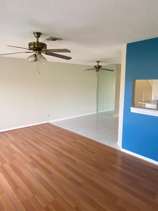 unfurnished room featuring light wood-type flooring, baseboards, and a textured ceiling