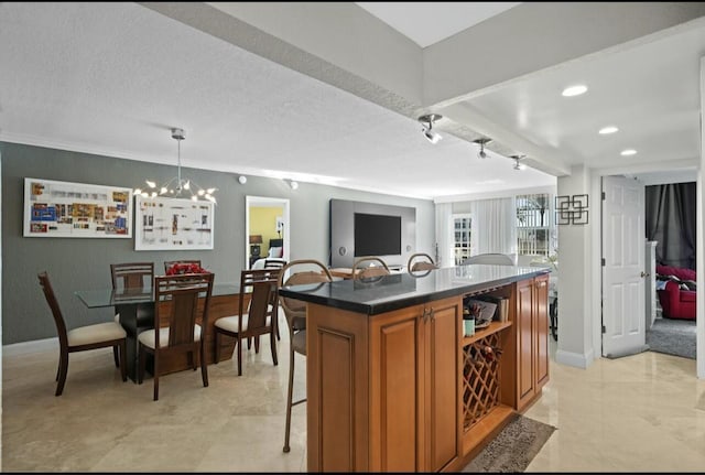 kitchen featuring a textured ceiling, a breakfast bar area, a kitchen island, brown cabinetry, and dark countertops