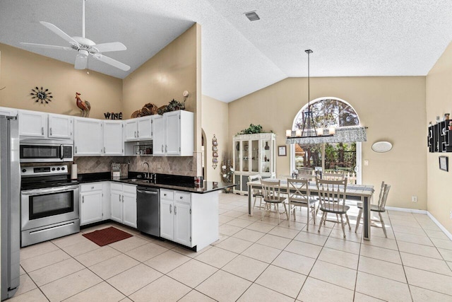 kitchen featuring light tile patterned floors, dark countertops, decorative backsplash, appliances with stainless steel finishes, and a sink