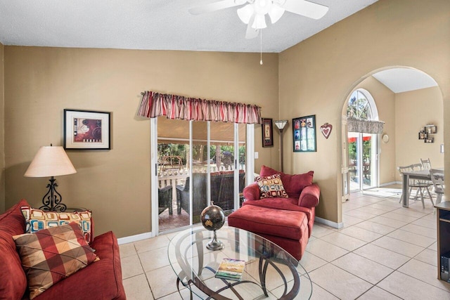 living room featuring light tile patterned floors, arched walkways, lofted ceiling, and baseboards