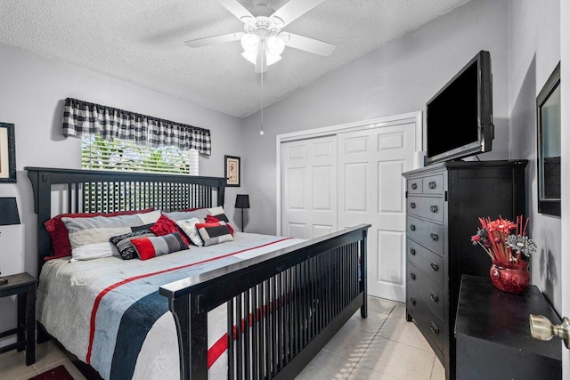 bedroom with vaulted ceiling, a closet, light tile patterned flooring, and a textured ceiling