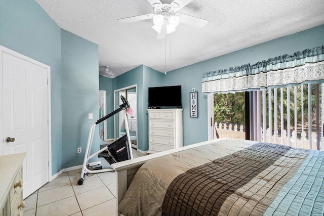 bedroom featuring light tile patterned floors, a closet, ceiling fan, a textured ceiling, and baseboards