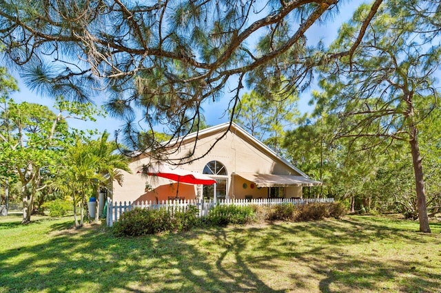 rear view of house featuring a fenced front yard and a lawn