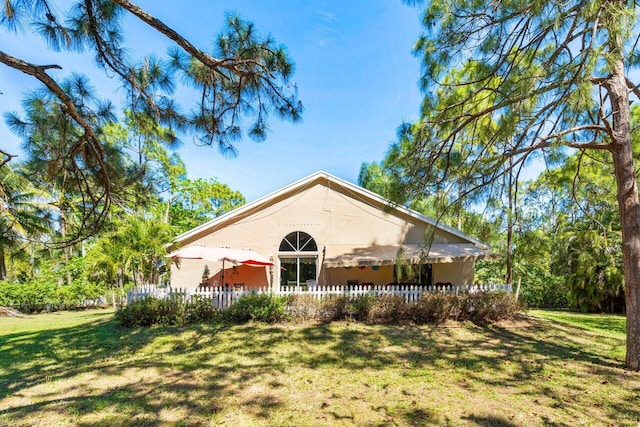 rear view of property with fence and a lawn